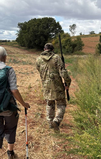 Armed man in camoflage jacket leading a walker